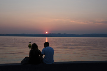 Naklejka na ściany i meble tramonto persone al tramonto guardare il tramonto cigno al tramonto mare lago estate spettacolo natura sole, 