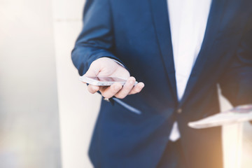 Businessman with telephone in hand and holding a newspaper. Stylish man at the railway station in a blue jacket.