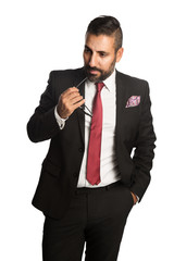 An attractive businessman wearing a black suit and red tie, standing relaxed against a white...