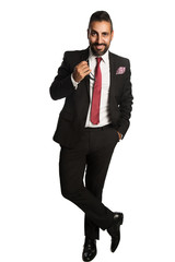 An attractive businessman wearing a black suit and red tie, standing relaxed against a white background with sunglasses in his hand.