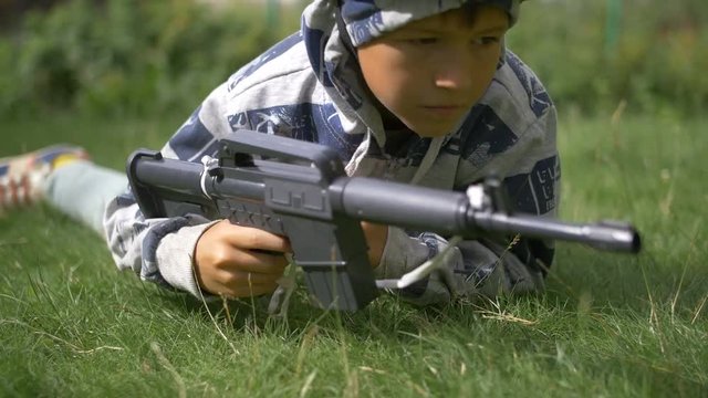 boy in camoflauge playing war shoots a toy gun