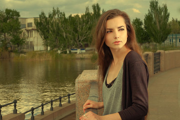 Pretty girl wearing black shirt, standing against fence by Volga River in Astrakhan in summer,...