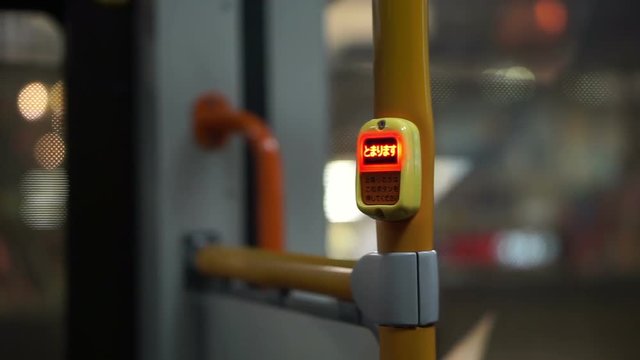 View inside the night city bus. Abstract public transportation in Asia. Stop button in car