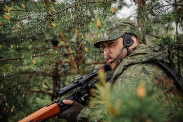 army soldier holding sniper rifle with scope and aiming in forest. war, army, technology and people...
