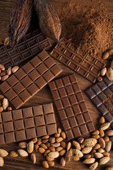 Chocolate bar, candy sweet, cacao beans and powder on wooden bac