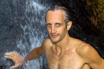 Man relaxing under waterfall. outside