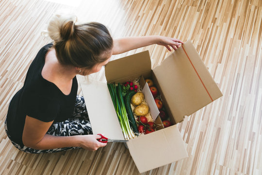 Frau &ouml;ffnet Kiste mit Lebensmitteln, Lieferservice per postsend