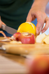 Frau schneidet eine Zitrone auf, Äpfel im Vordergrund