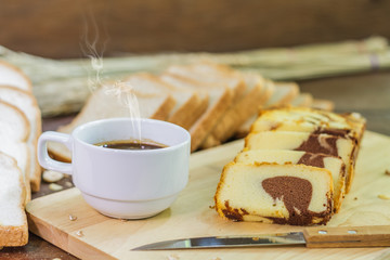Butter cake sliced and hot coffee on wood table.