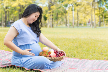 Pregnant woman holding her belly and healthy fruit which good for health.