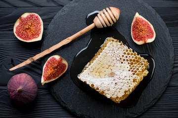 Above view of a honeycomb, liquid honey and sliced figs