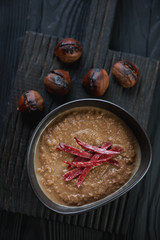 Above view of chestnut cream-soup on a dark wooden serving board