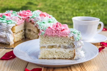 Piece of sponge cake  with curd cream  and banana on  background of cake and cup of coffee