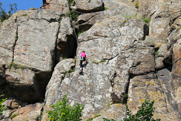 Girl rock climber climbs on a rock