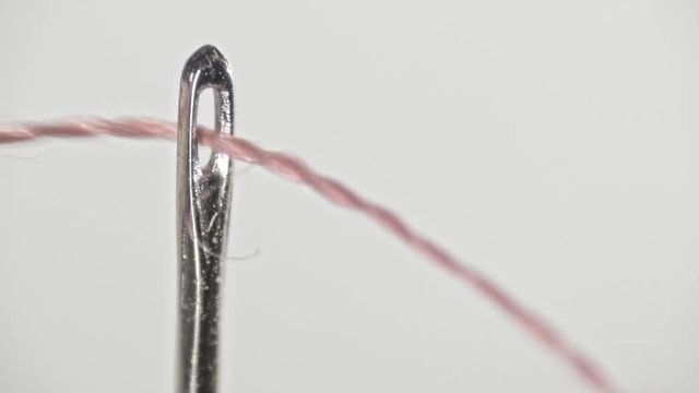 Close up passing a thread through a needle