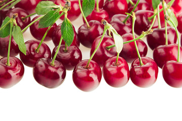 Bunches of ripe cherries with leaves on a white background. Isolated. Decorative fruit border. Food background. Copy space.