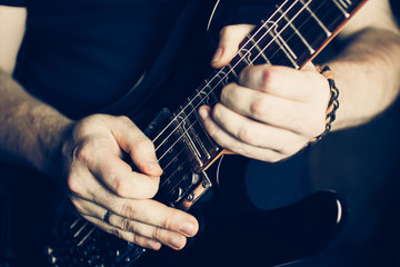 Musician playing electric guitar superstrat type, hands in focus