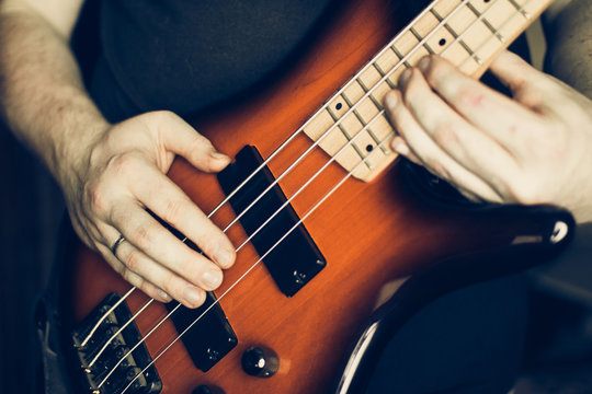 Musician playing electric bass guitar, hands in focus