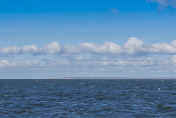 blue sea and sky. The ship sails past the coast with the settlement and now.