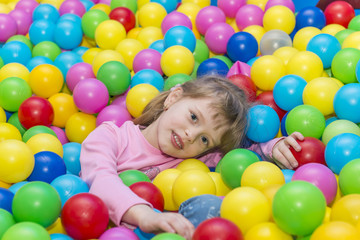 Fototapeta na wymiar Happy children playing and having fun at kindergarten with colorful balls, a child in the pool with balls.