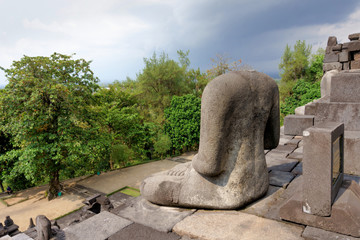 The damaged Buddha statue at Borobudur temple , the 9th century Buddhist temple in Magelang Regency...