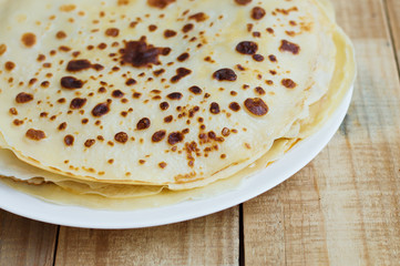 Pile of fresh homemade crepes on wooden table. Thin pancakes on rustic background