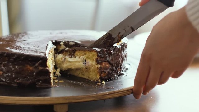 Person cutting a brown cake with a knife