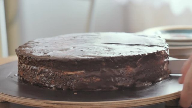Person cutting a brown cake with a knife