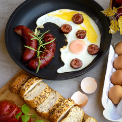 Fried sausages and eggs in a pan served with bread, tomatoes and egg shell, TOP VIEW
