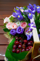 basket of flowers and cherries closeup with wooden background