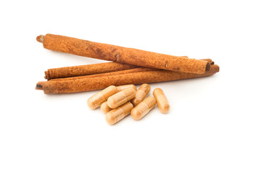 herbal powder in capsule and cinnamon on white background