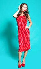 Beautiful brunette girl in a red dress on a blue background.