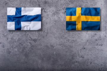 Flags of the finland and sweden on concrete background.