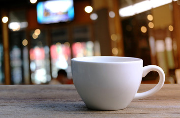 White Coffee cup on wooden table in coffee shop blur background.