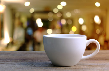 White Coffee cup on wooden table in coffee shop blur background.