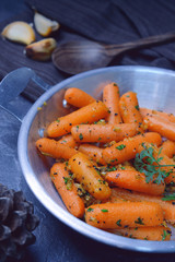 Mini carrots stir fry with garlic, honey, butter, salt, black pepper and parsley on pan.