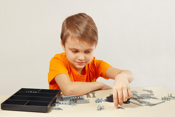 Young engineer is going to play with mechanical constructor at the table