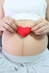 Red heart symbol in hand a asian women pregnant.