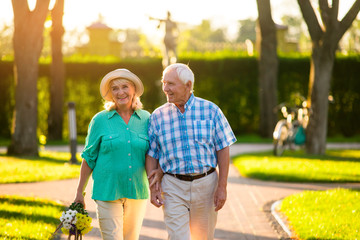 Naklejka premium Elderly couple on nature background. Man and woman with bouquet. Love tested by time. Stay devoted and honest.