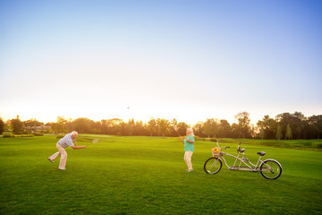 Senior couple plays badminton. Bike on the lawn. The score is equal. Sport in our life.