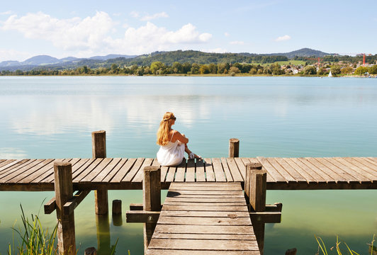 Girl on the wooden jetty at the lake. Switzerland