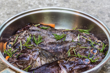 Marine ruff with carrots and rosemary in a pan on grey backgroun