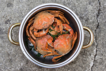 Boiled red crabs in a pot with herbs, top view, close up