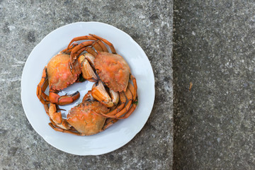 Three red boiled crabs on white dish, top view, free space