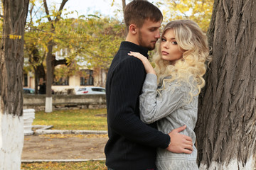 fashion outdoor photo of beautiful tender couple, wearing cozy clothes, walking by autumn park 