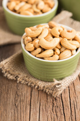 Cashew nuts in ceramic green on the old wooden table.