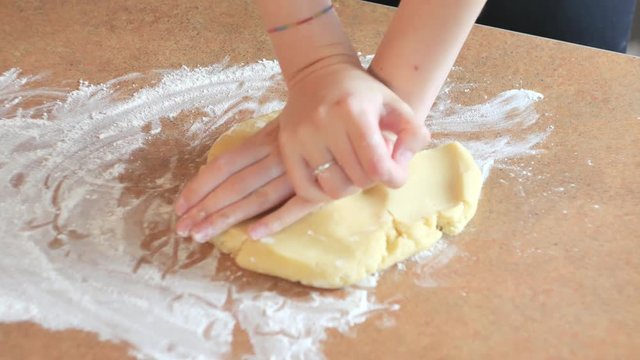 Female hands kneading dough in flour on table. prepares bread or apple pie