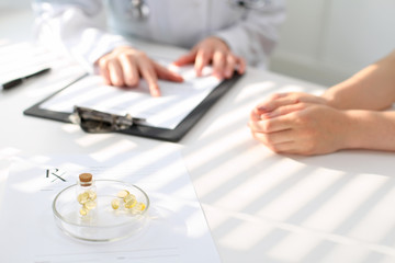 Medicine capsules and pills are lying against the background of a doctor and patient