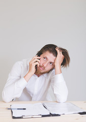 portrait of frustrated man working on laptop, talking on phone and getting problems at work