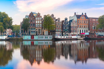 Amsterdam canal Amstel with typical dutch houses and boats during sunrise, Holland, Netherlands.